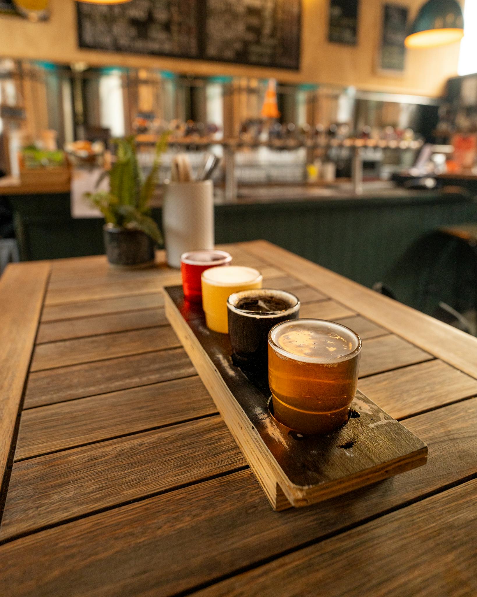 A selection of craft beers served on a rustic wooden table inside a cozy bar.